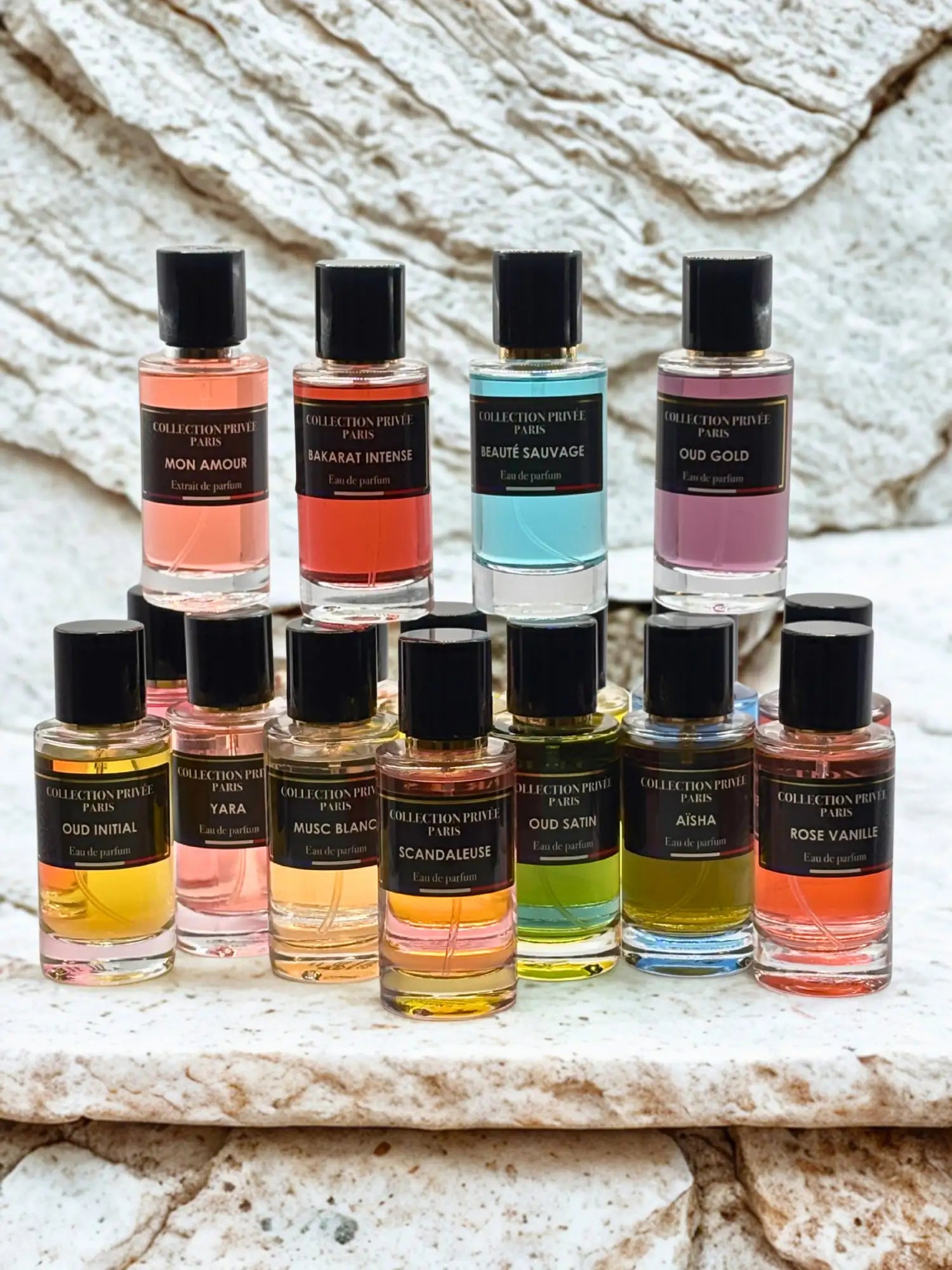 Une collection de flacons de parfum Collection Privée Paris, chacun avec un bouchon noir élégant et un corps en verre clair mettant en valeur des liquides colorés vibrants.